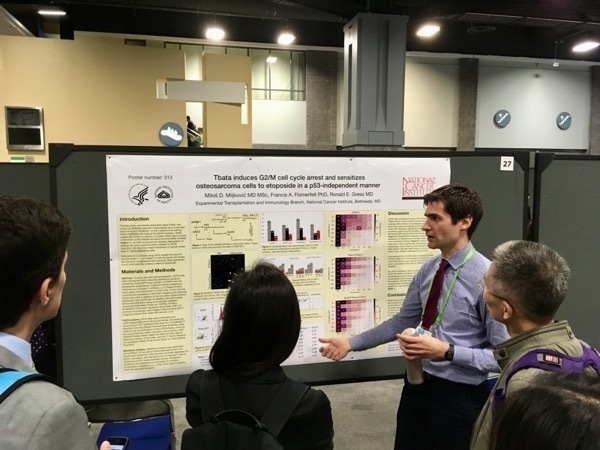 Milos standing in front of a large poster titled Tbata induces G2/M cell cycle arrest and sensitizes osteosarcoma cells to etoposide in a p53-independent manner.
