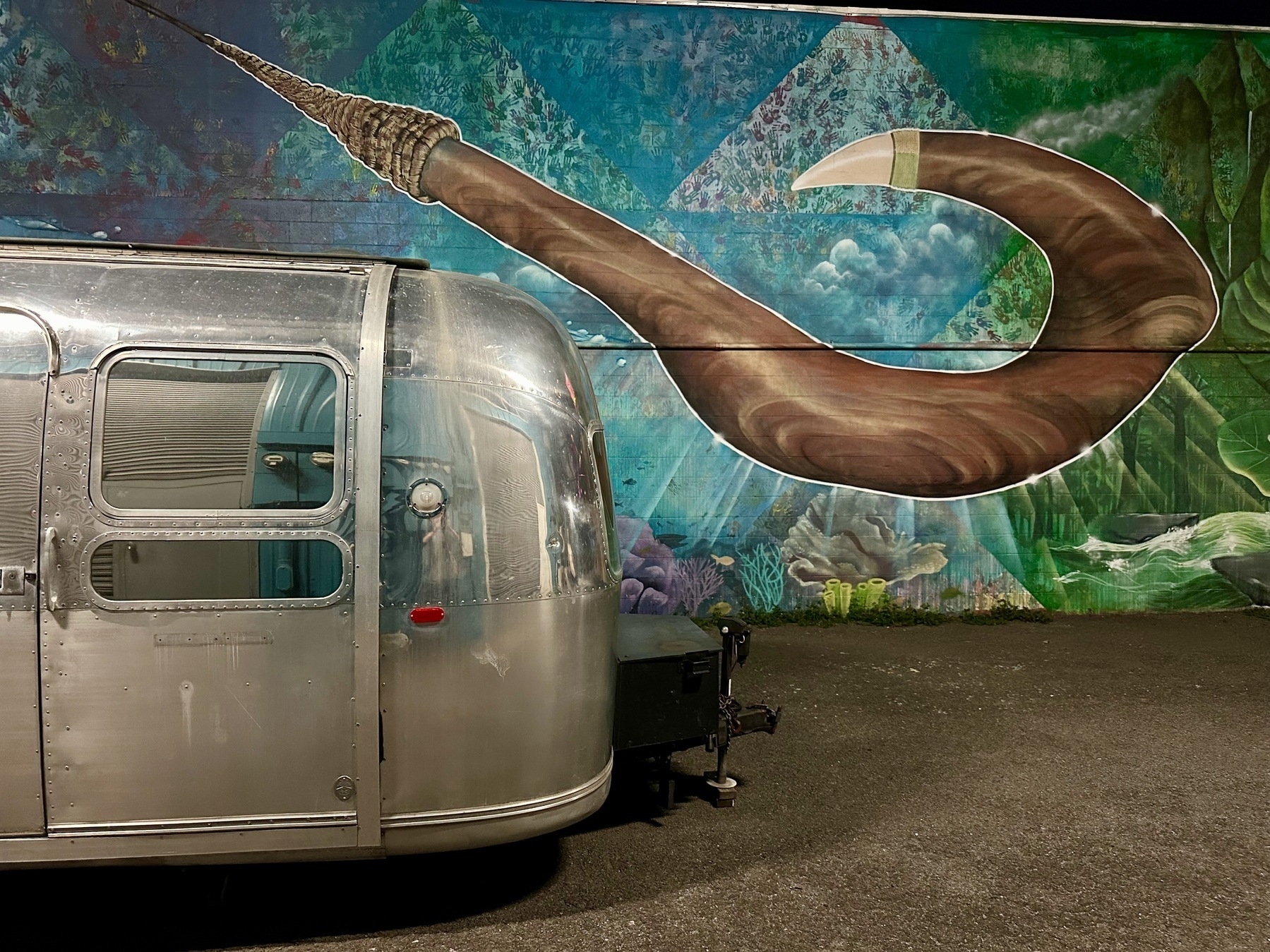 Photo of a shiny metal trailer in front of a mural depicting a fish hook.