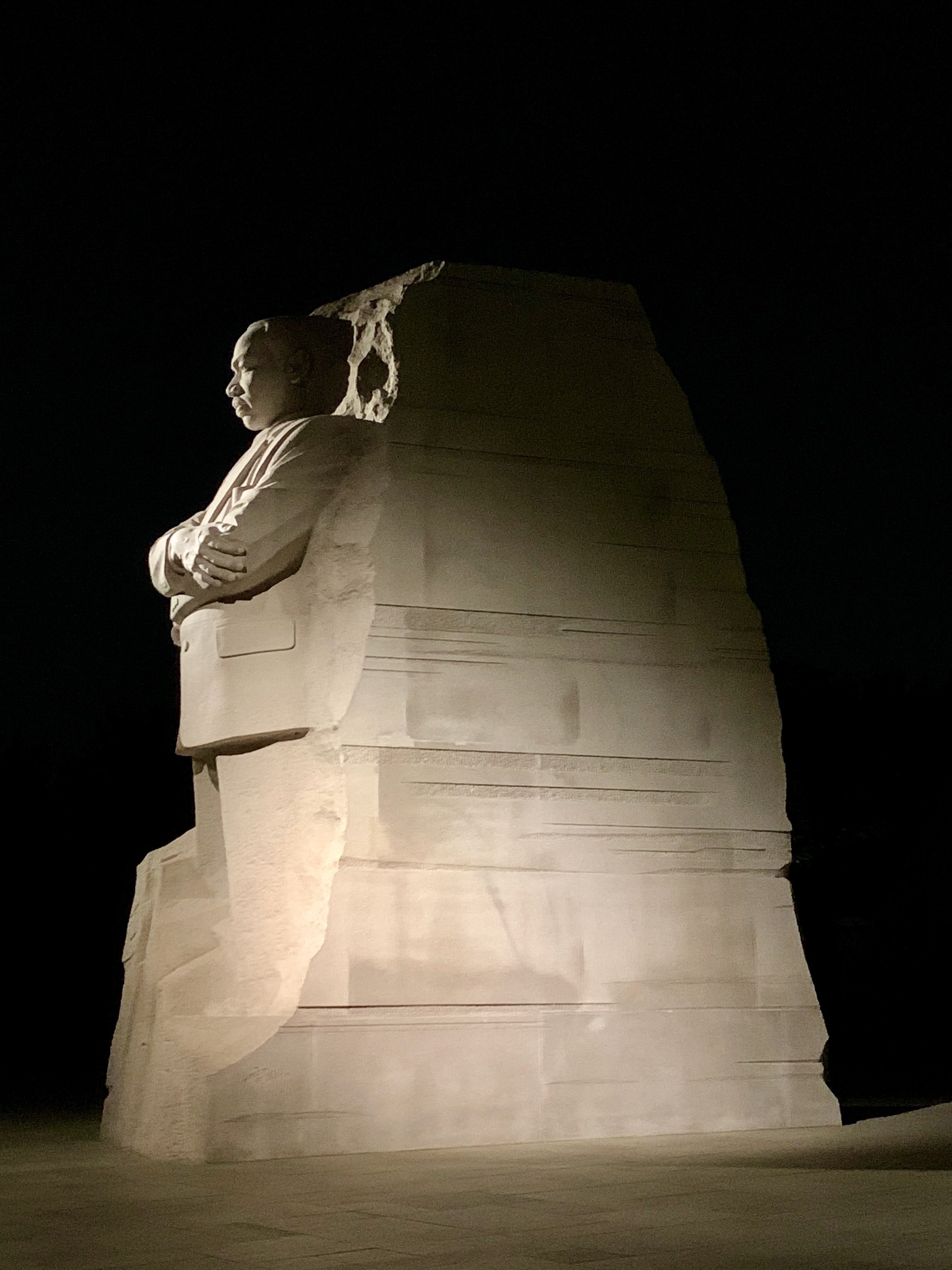 Photo of the white granit MLK memorial in Washington DC set against the black night time sky.