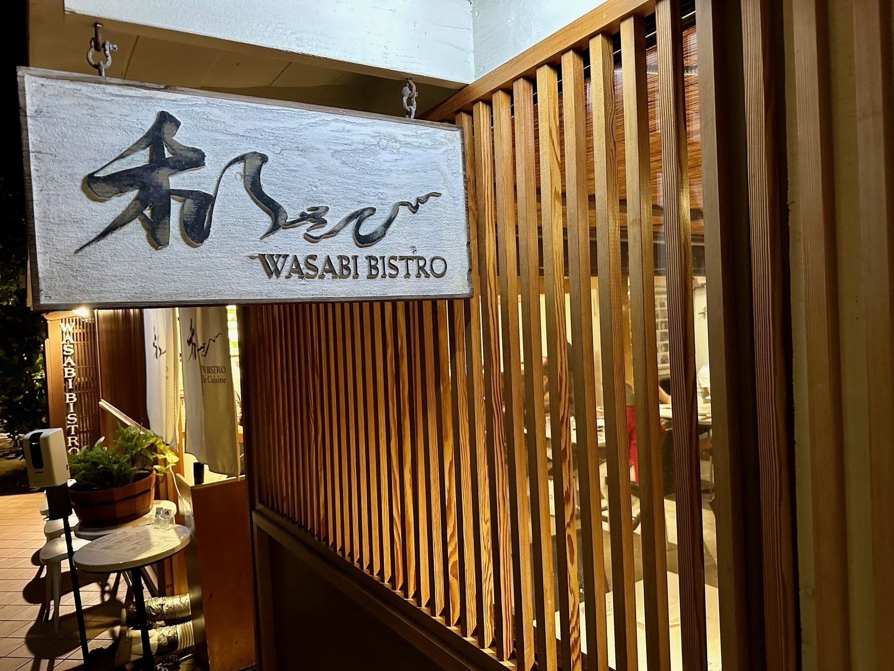Photo of the entrance to the Wasabi Bistro with the restaurant interior visible between wood slats.
