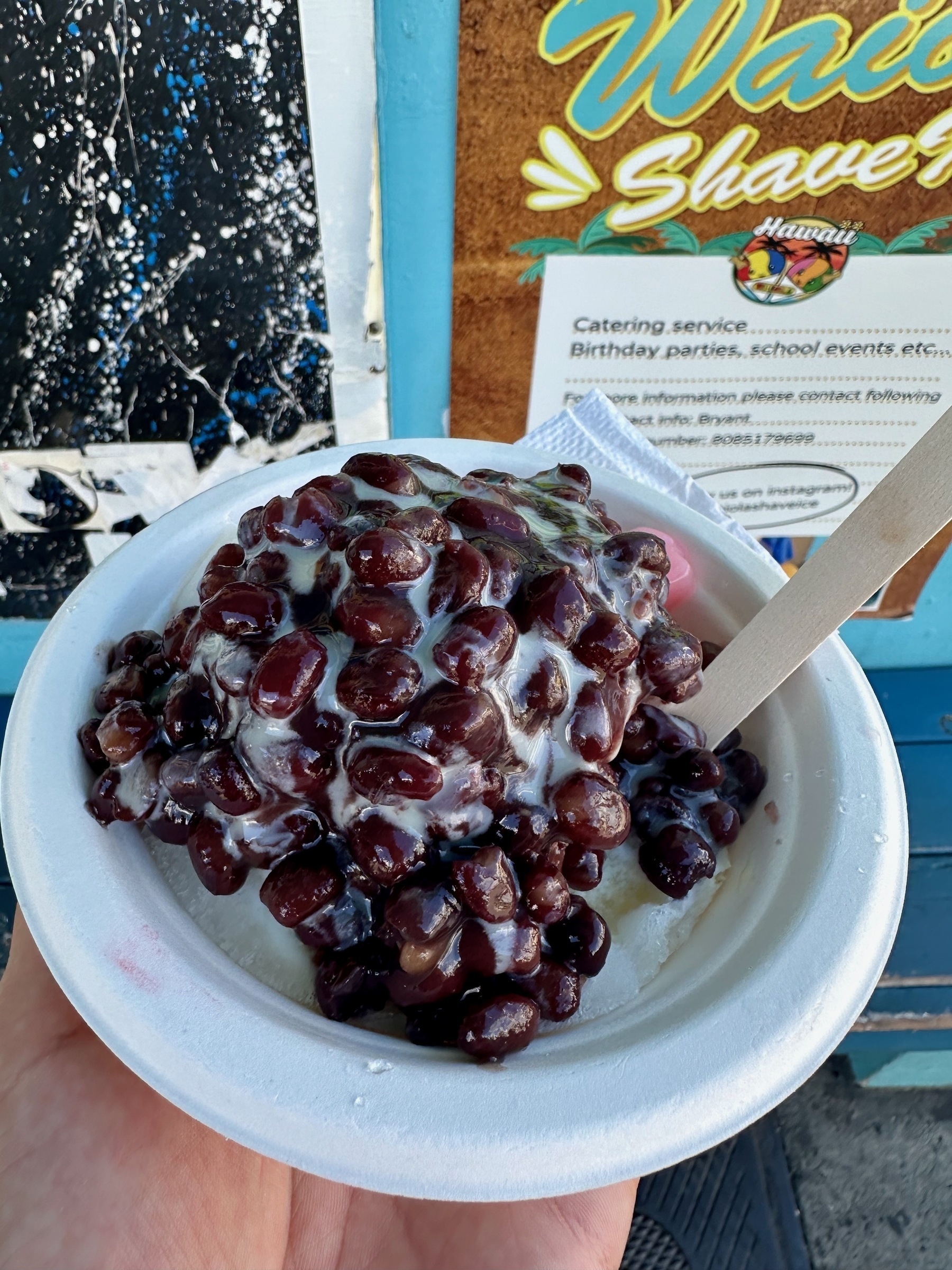 A paper bowl with a pile of read beans covered in syrup.