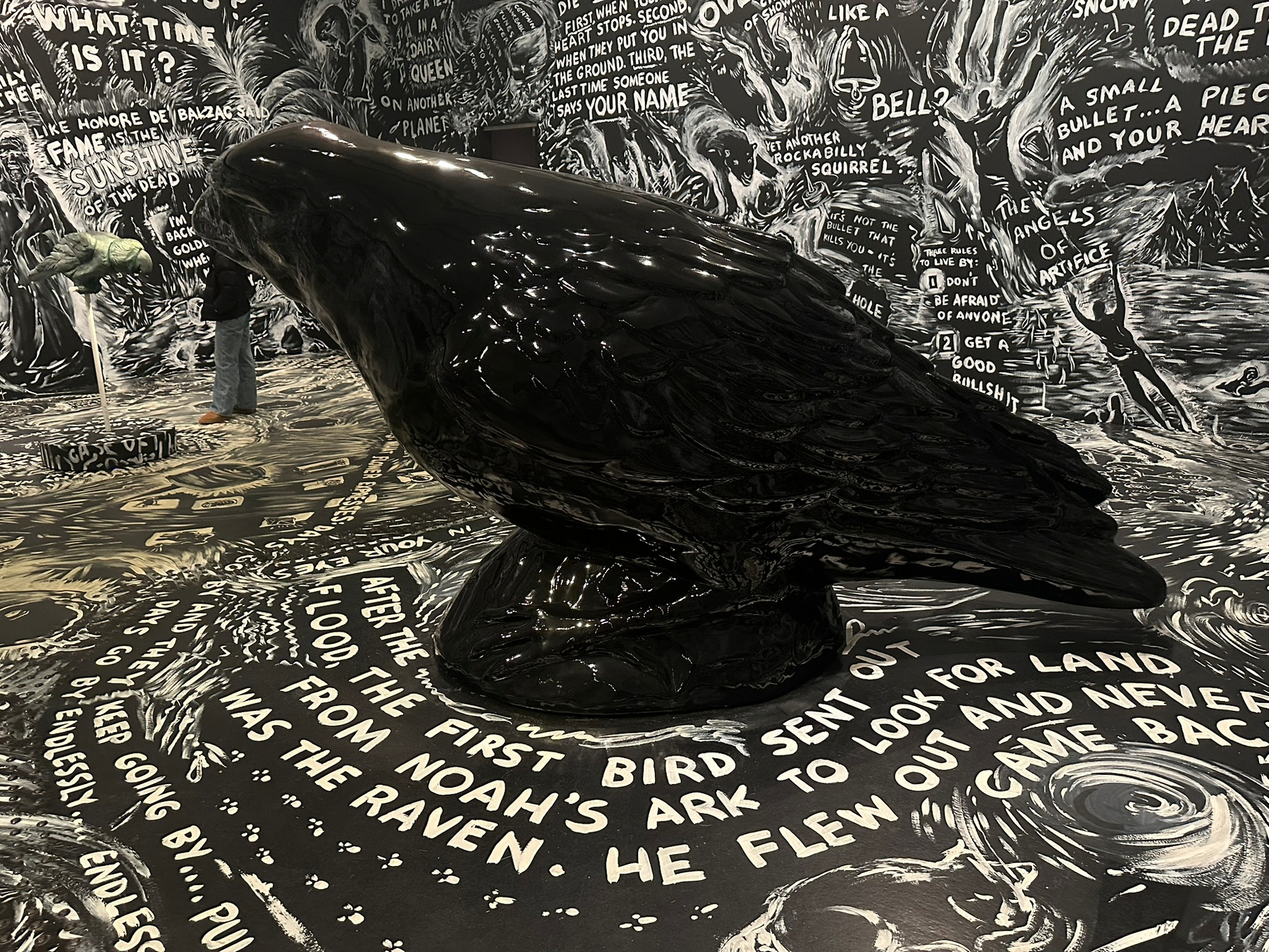 A large ceramic statue of a crow inside a room covered in black and white graphiti.