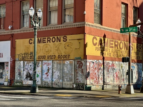 A boarded up store front for a used and new book store on Portland's 3rd Avenue SW. Sign above says Cameron's Books.